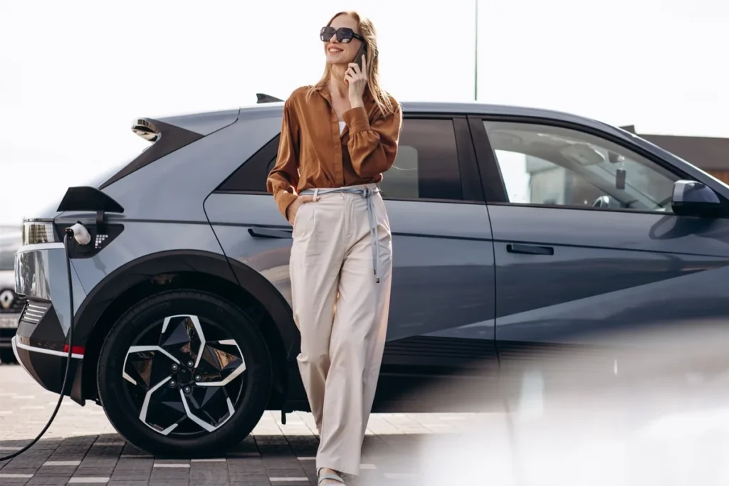 masina din profil la incarcat cu o femeie care vorbeste la telefon